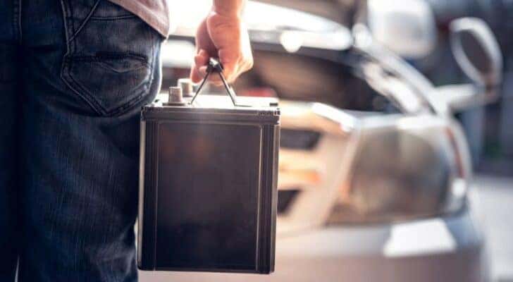 A person is shown carrying a battery.