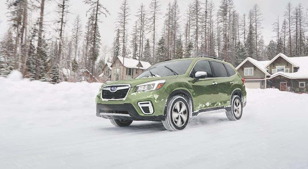 A green 2019 Subaru Forester is shown driving on snow.