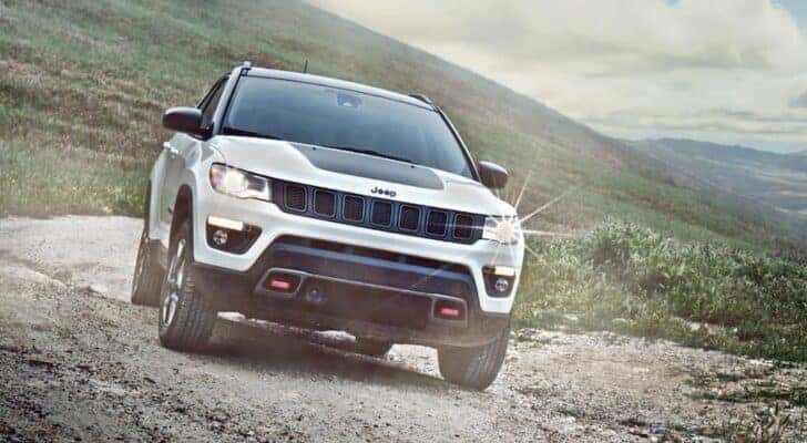 A white 2020 Jeep Compass Trailhawk is shown from the front on a trail.
