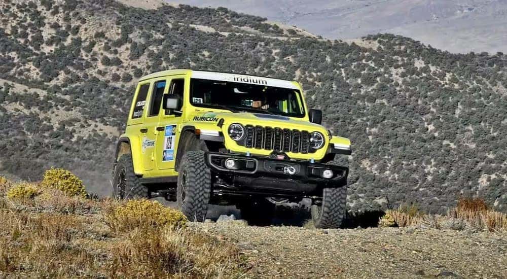 A green 2023 Jeep Wrangler 4xe Rubicon is shown off-roading.