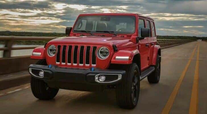 A red 2022 Jeep Wrangler is shown driving on a bridge after trying to buy a used Jeep.
