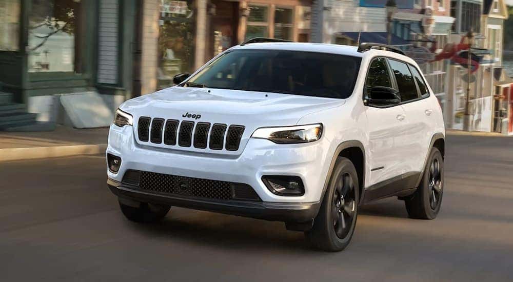A white 2023 Jeep Cherokee Altitude LUX is shown driving on a city street.