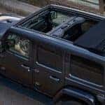 A black 2024 Jeep Wrangler is shown driving on a bridge.
