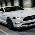 One of the more common used cars for sale, a white 2020 Ford Mustang GT, is shown driving in a tunnel.