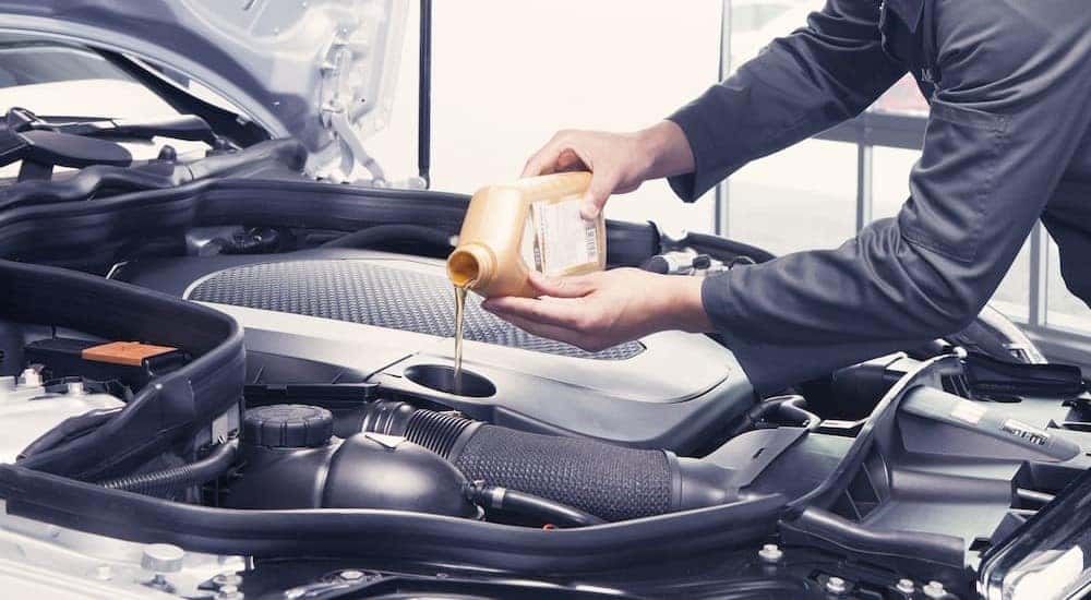 A mechanic is shown pouring oil.
