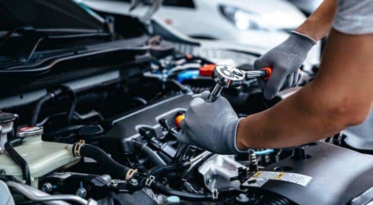 A mechanic is shown performing auto repair on an engine block.