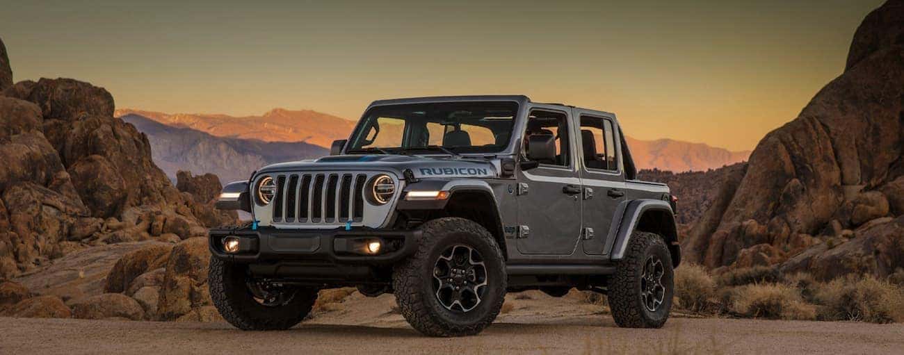 A grey 2021 Jeep Wrangler 4xe Rubicon parked in the mountains at sunset.