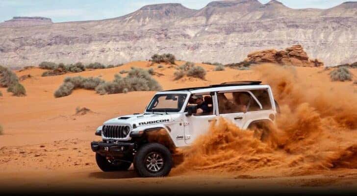 A white 2024 Jeep Wrangler Rubicon 392 is shown off-roading.