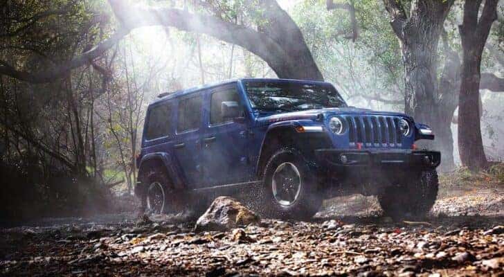 A blue 2020 Jeep Wrangler Unlimited Rubicon is shown driving off-road.