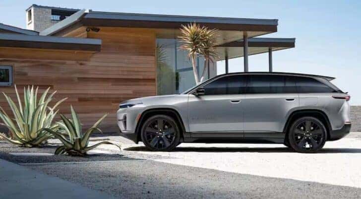 A silver 2024 Jeep Wagoneer S for sale is shown parked near a house.