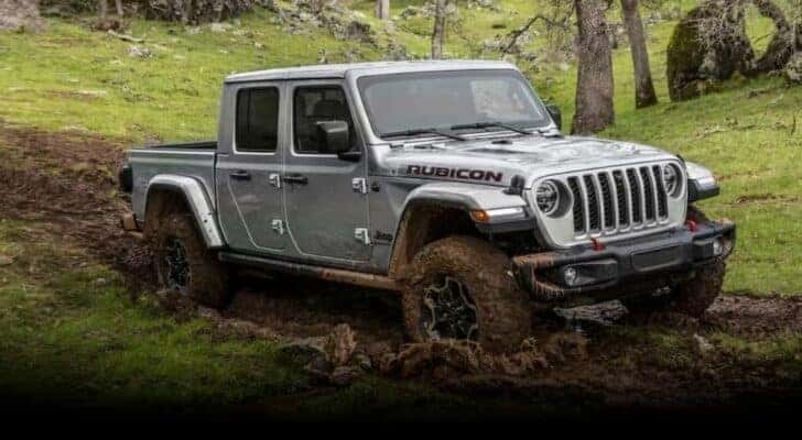 A silver 2023 Jeep Gladiator Rubicon is shown driving off-road after viewing a used Jeep Gladiator for sale.