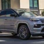 A grey 2022 Jeep Compass driving to a used car dealer.