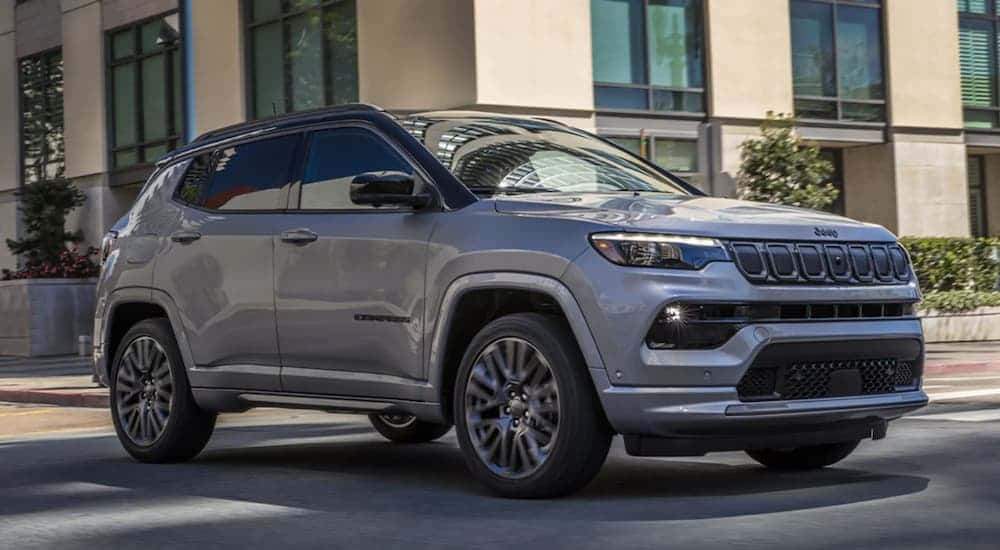 A grey 2022 Jeep Compass driving to a used car dealer.