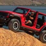 A red 2025 Jeep Wrangler Rubicon is shown off-roading.