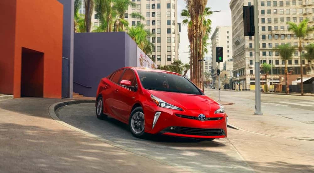 A red 2022 Toyota Prius driving on a city street.