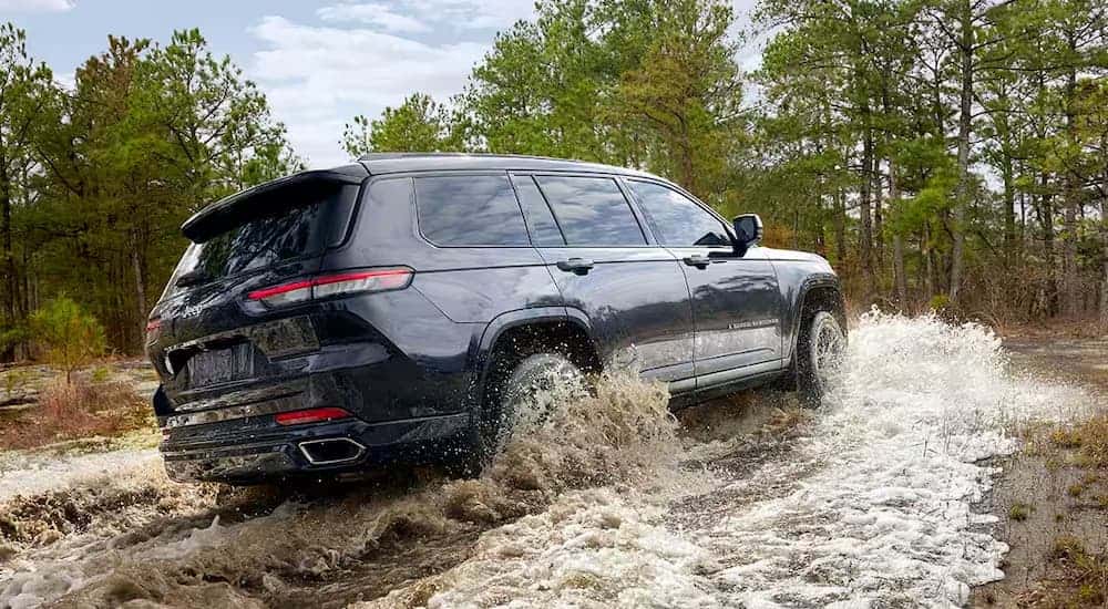 Black 2025 Jeep Grand Cherokee off-roading in a river.