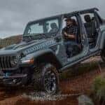 A gray 2025 Jeep Wrangler 4xe Rubicon is shown off-roading.