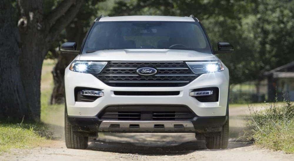 A white 2023 Ford Explorer King Ranch driving on a dirt road.