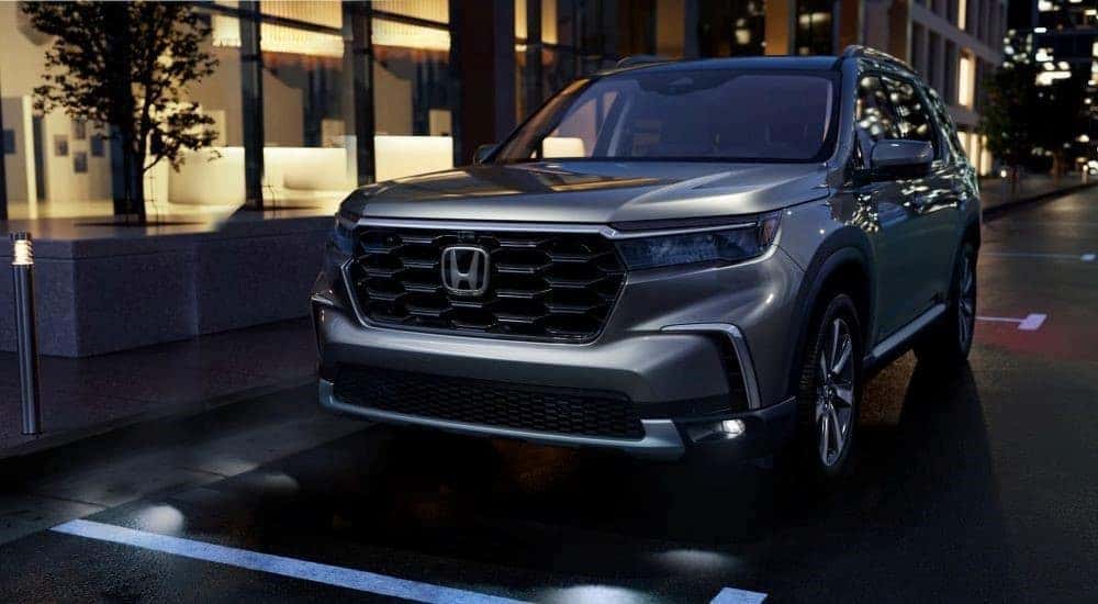 A silver 2023 Honda Pilot Elite parked in a city.