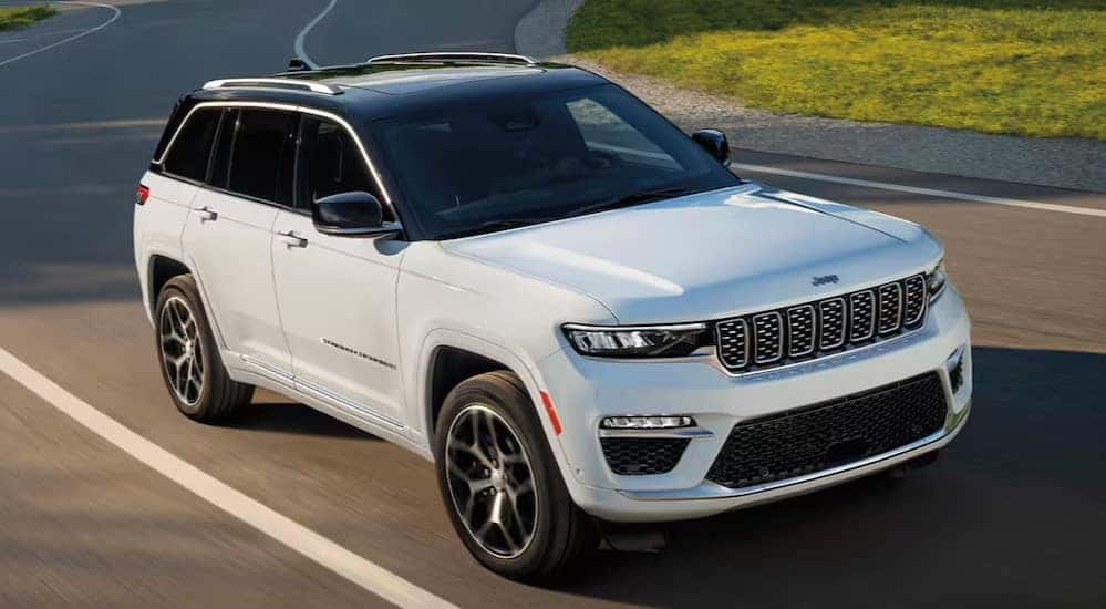 A white 2024 Jeep Grand Cherokee driving to view used SUVs for sale near Pueblo.