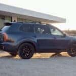 A blue 2024 Kia Telluride parked on a driveway.