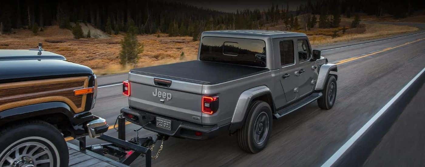 Rear of a grey 2022 Jeep Gladiator Wagoneer towing another vehicle.
