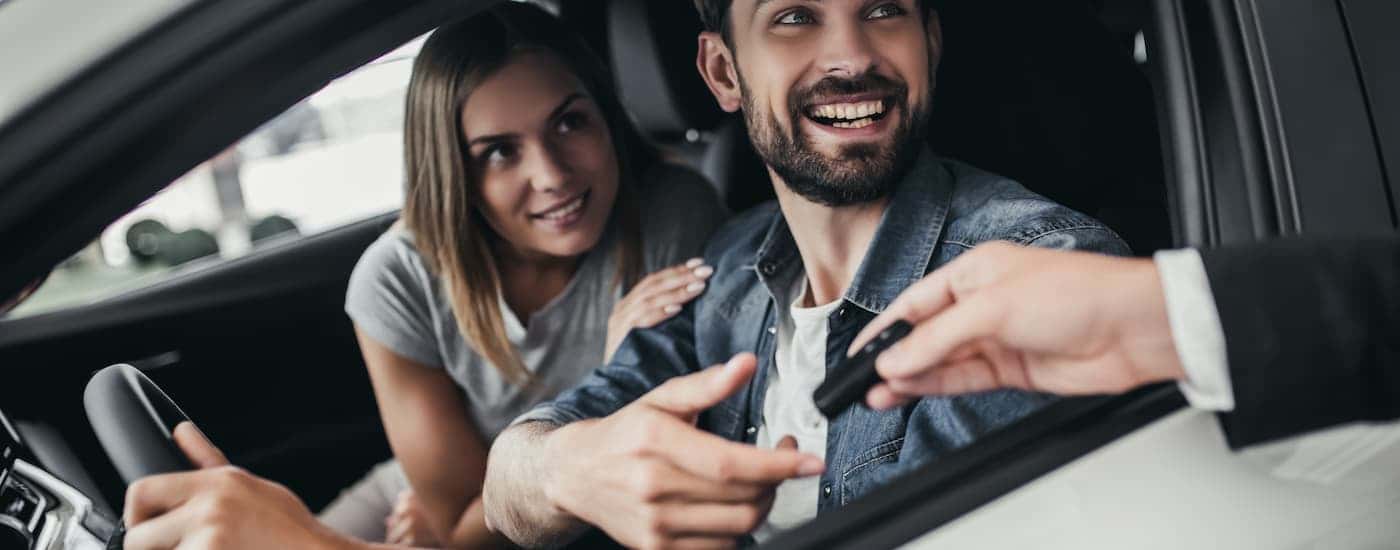 Couple smiling inside of their used vehicle they just purchased