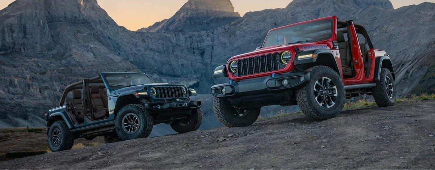 A grey and a red 2025 Jeep Wrangler parked off-road.