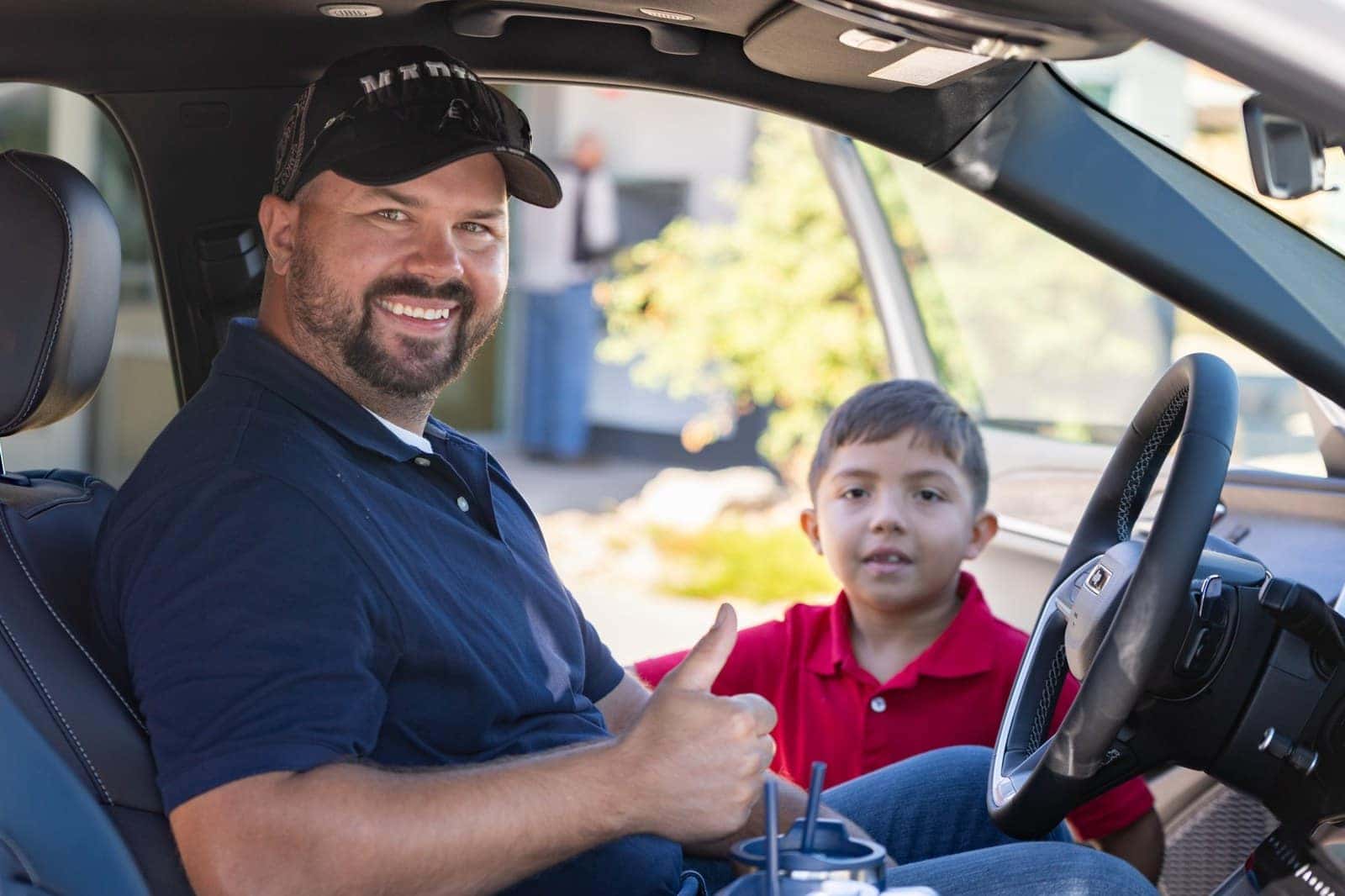 Marine Corps veteran Dustin Gabehart sits in the driver's seat of his new Jeep Grand Cherokee with his son