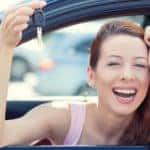 Woman, buyer sitting in her new car showing keys