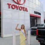 Miss Gaston County 2026 Catherine Lee pointing at Toyota of Gastonia sign