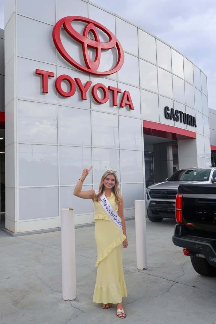 Miss Gaston County 2026 Catherine Lee pointing at Toyota of Gastonia sign